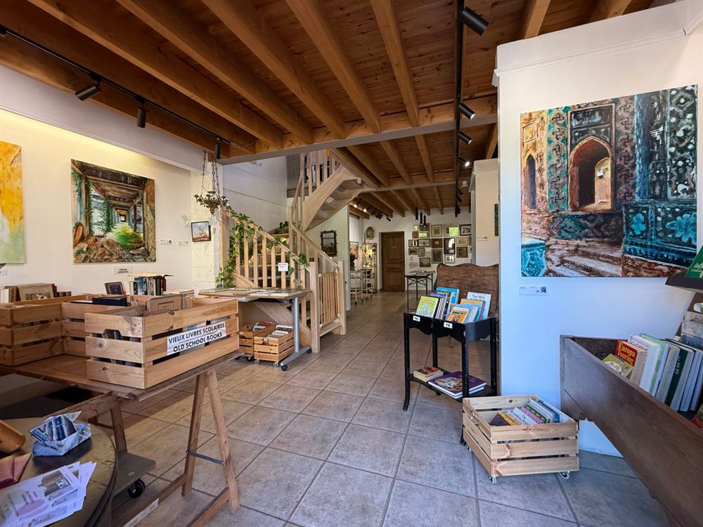 The front room with crates of books, a wooden staircase and paintings on the walls