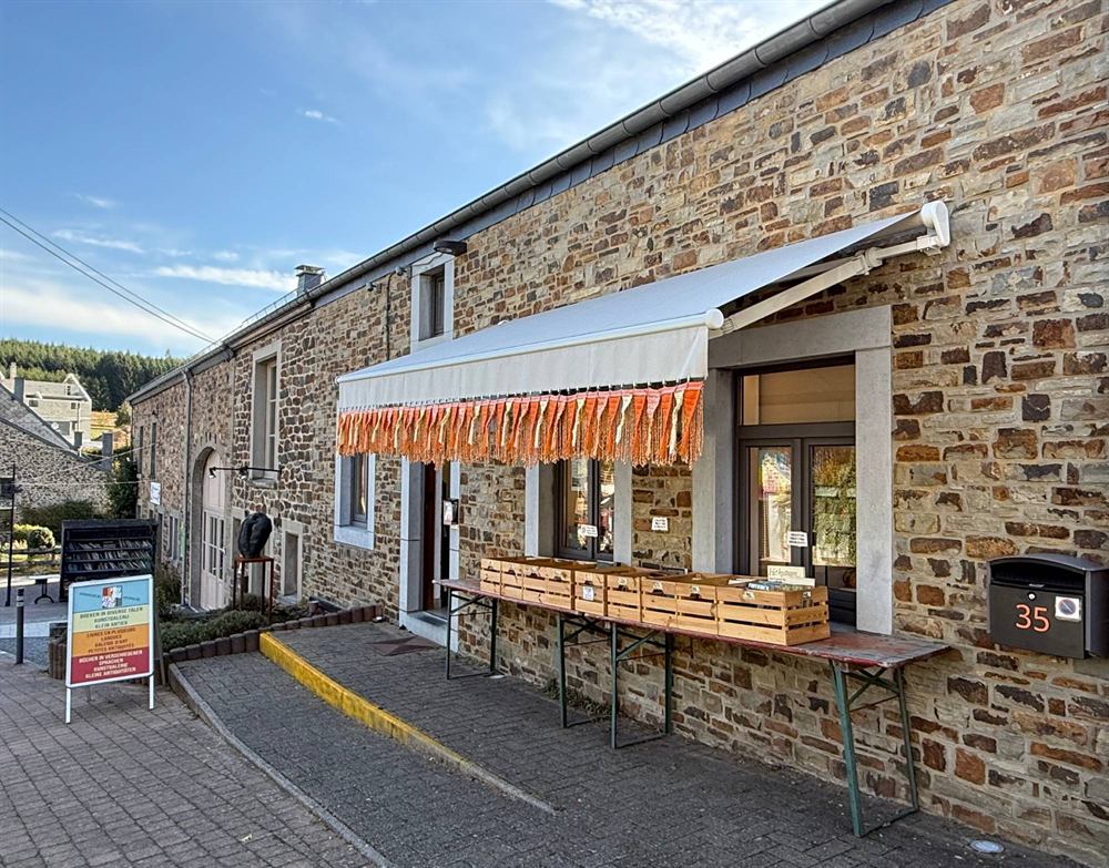 The stone front of the shop with an awning and trestle tables of books on the pavement